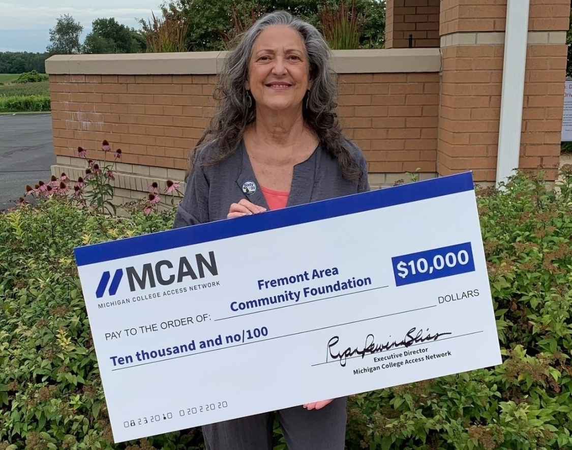 A woman holding a large check for a grant from MCAN